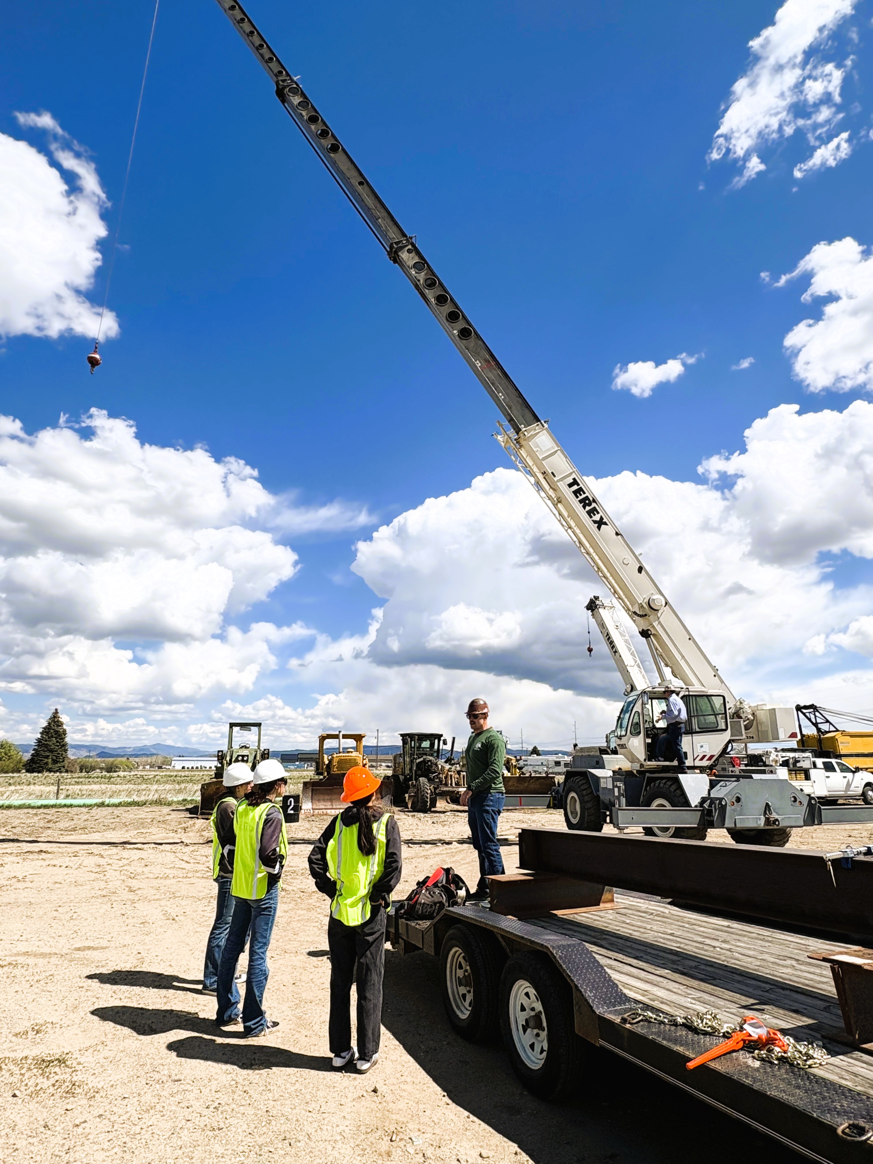 JMG students listening to a presentation while another student learns how to operate a crane